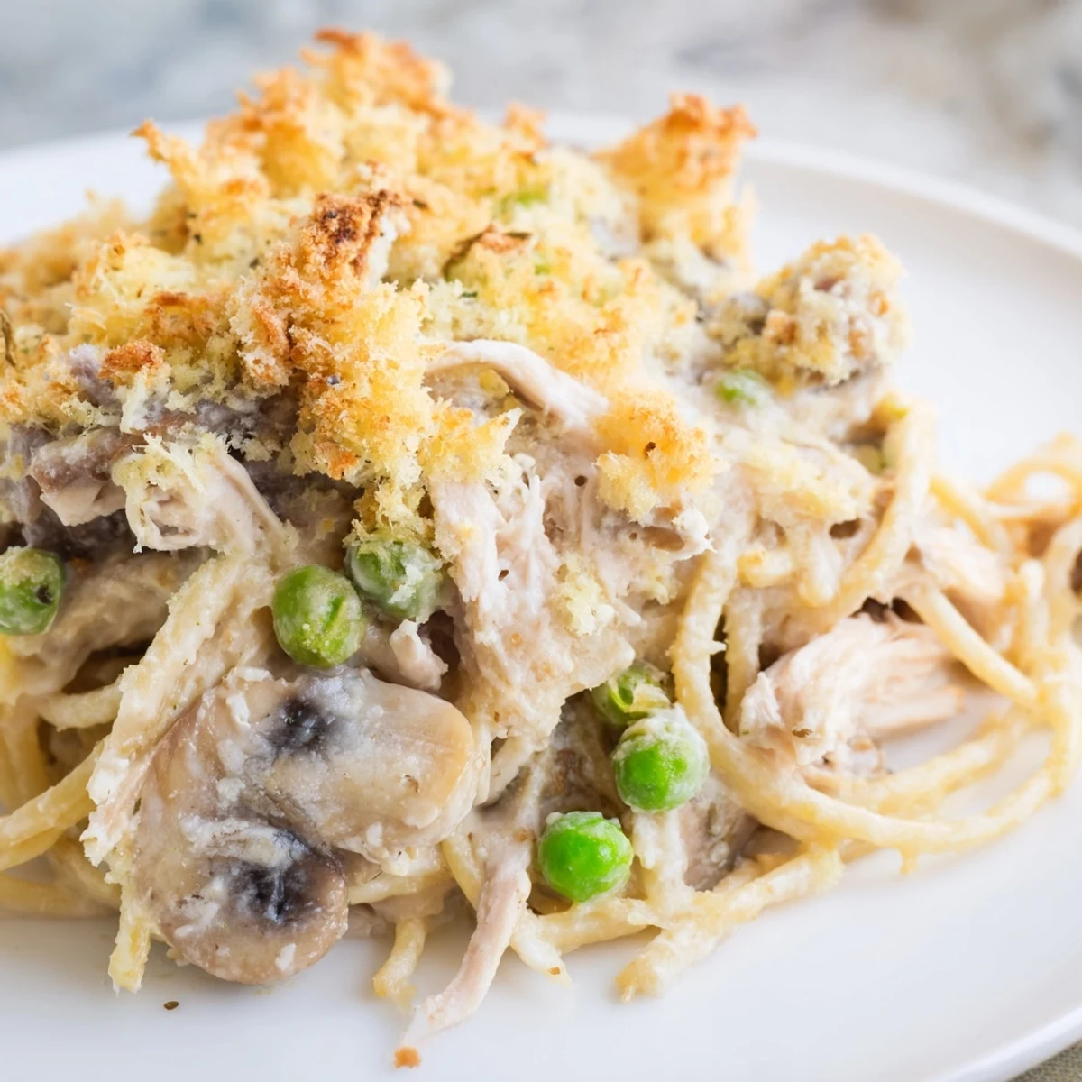 Fork-ready creamy Turkey Tetrazzini with tender turkey, mushrooms, and peas on a dinner plate.