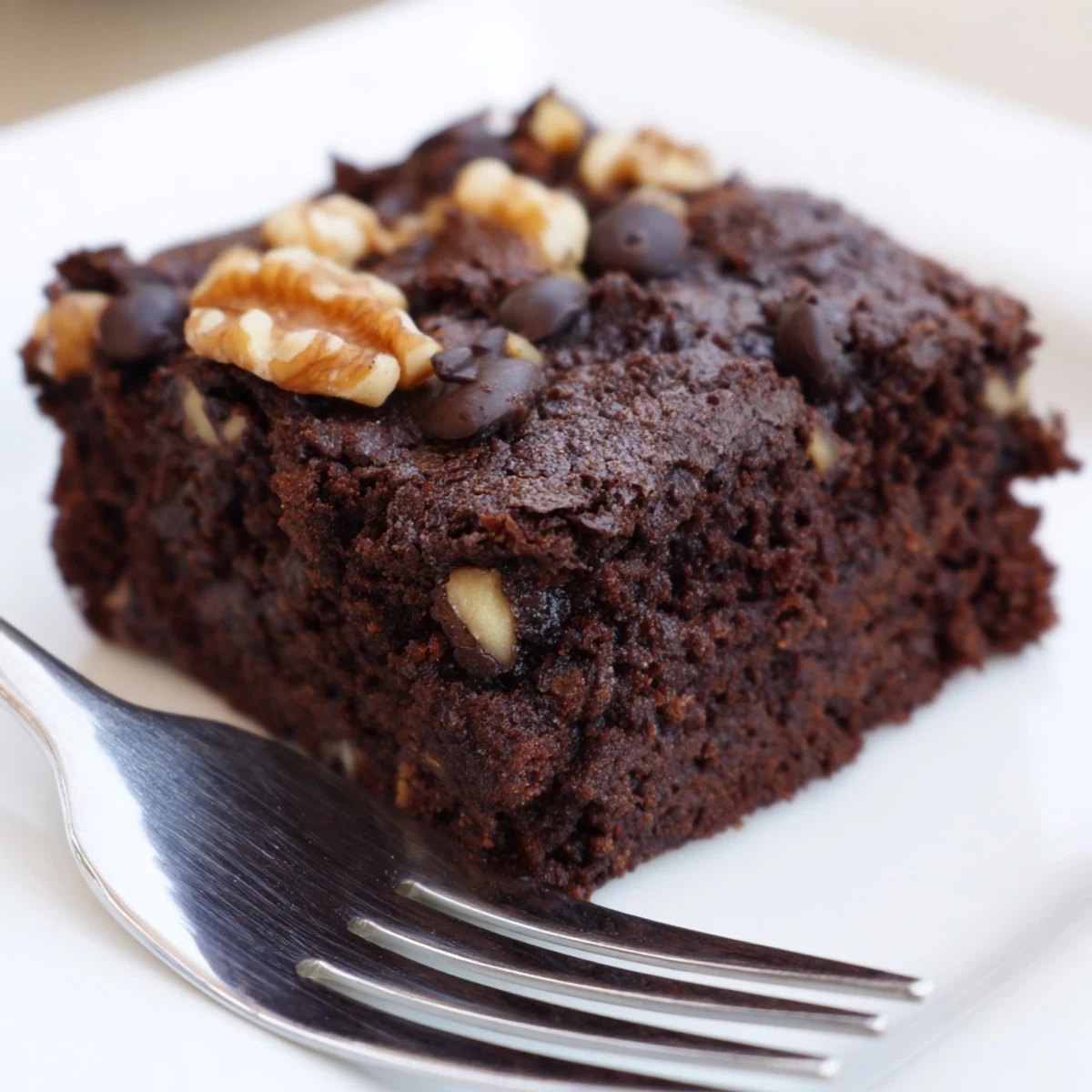A close-up of freshly baked Chocolate Brownies with Walnuts shows glossy chocolate chips melted into rich, dark squares ready to serve warm.