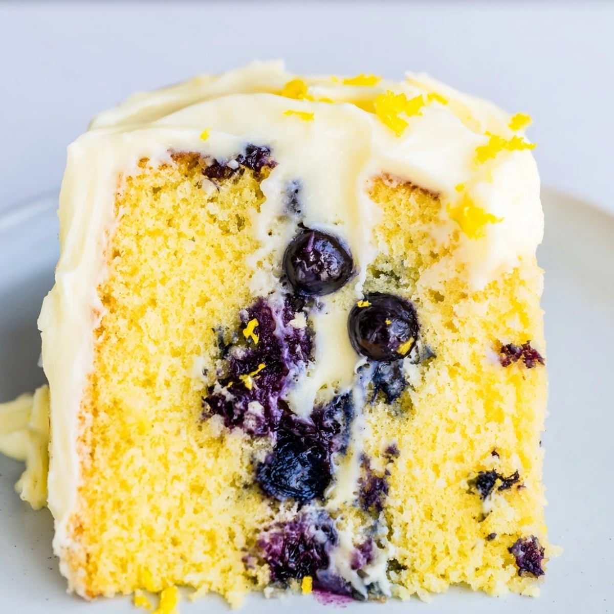 The freshly baked Lemon Blueberry Cake with frosting features golden edges and a luscious cream cheese layer, ready for a spring celebration.