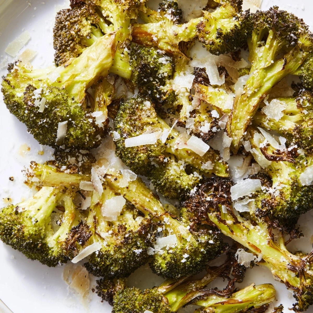 Roasted Broccoli with Garlic and Parmesan Cheese tossed in olive oil, roasted until tender with crisp edges on a baking sheet.