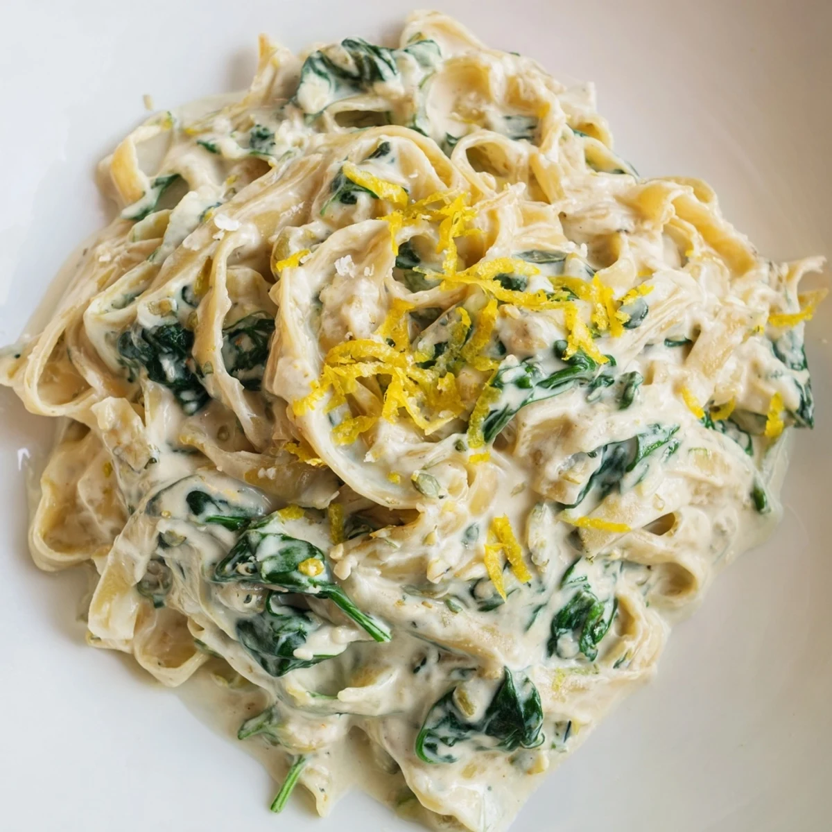 Creamy Spinach Pasta with Garlic and Lemon twirls in a skillet with a velvety sauce, ready for a weeknight dinner.