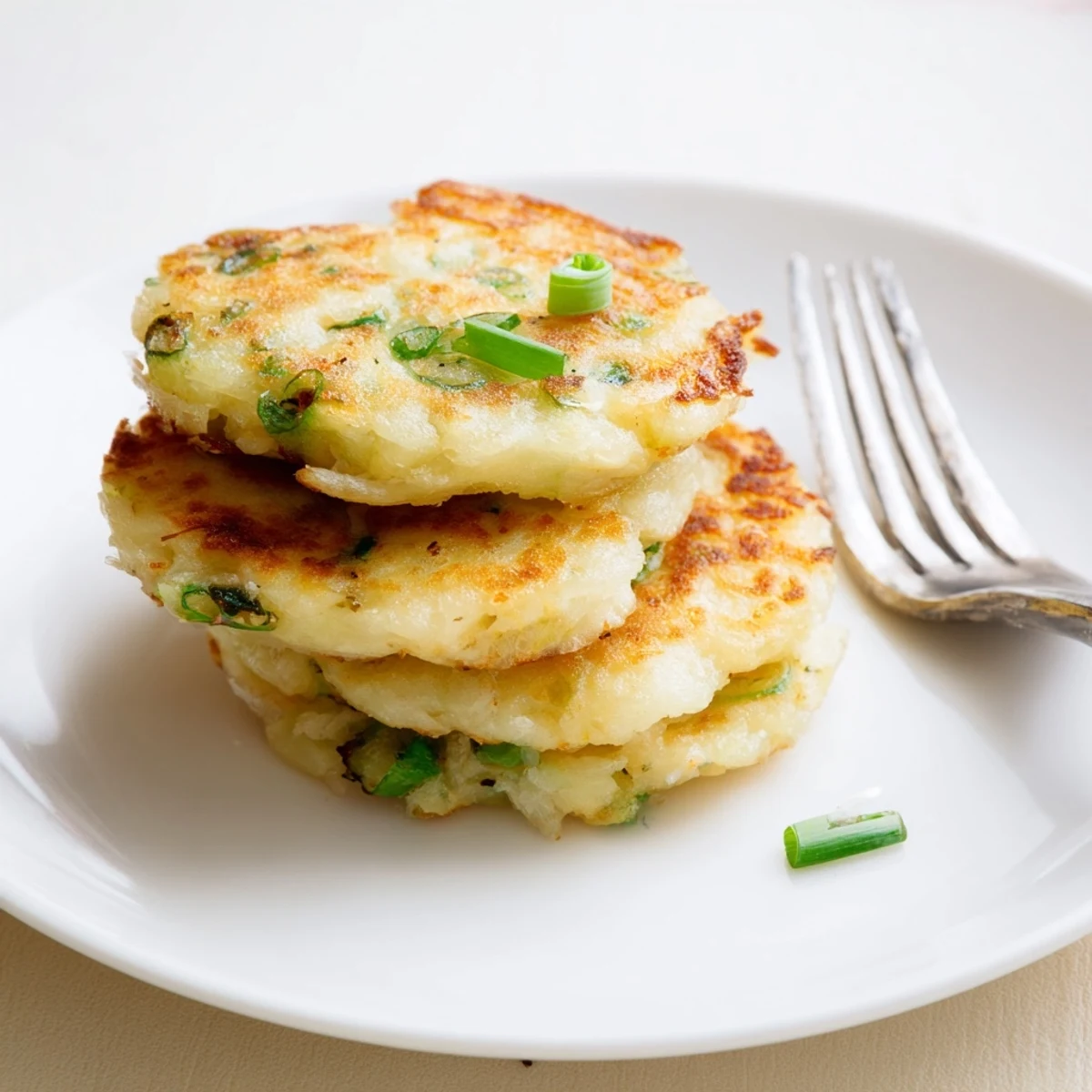 Savory Irish Potato Cakes with Scallions plated beside sour cream, perfect for a hearty American breakfast or brunch.