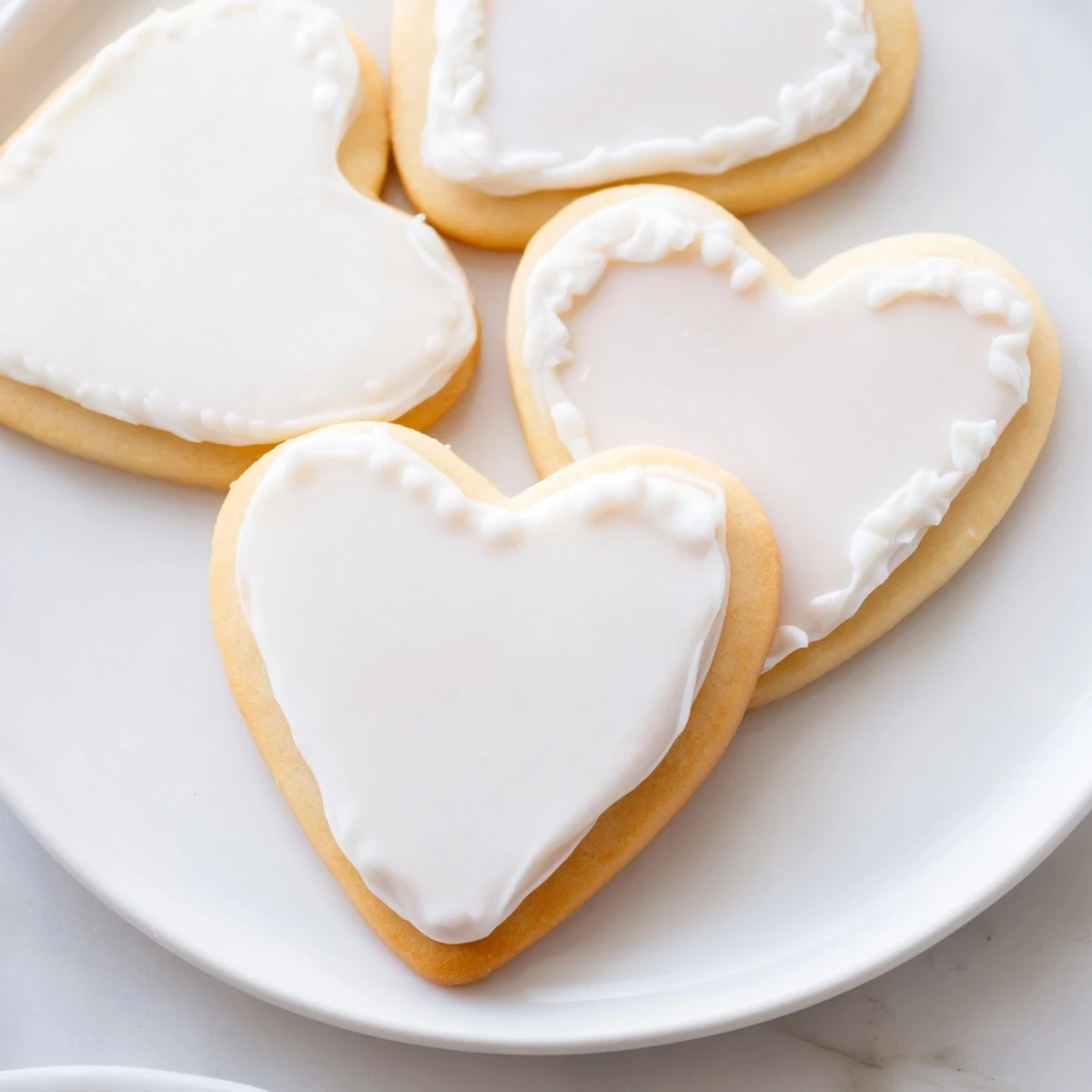 Bright red heart-shaped sugar cookies with crisp white royal icing, arranged on a cooling rack for a festive Valentine's treat.  