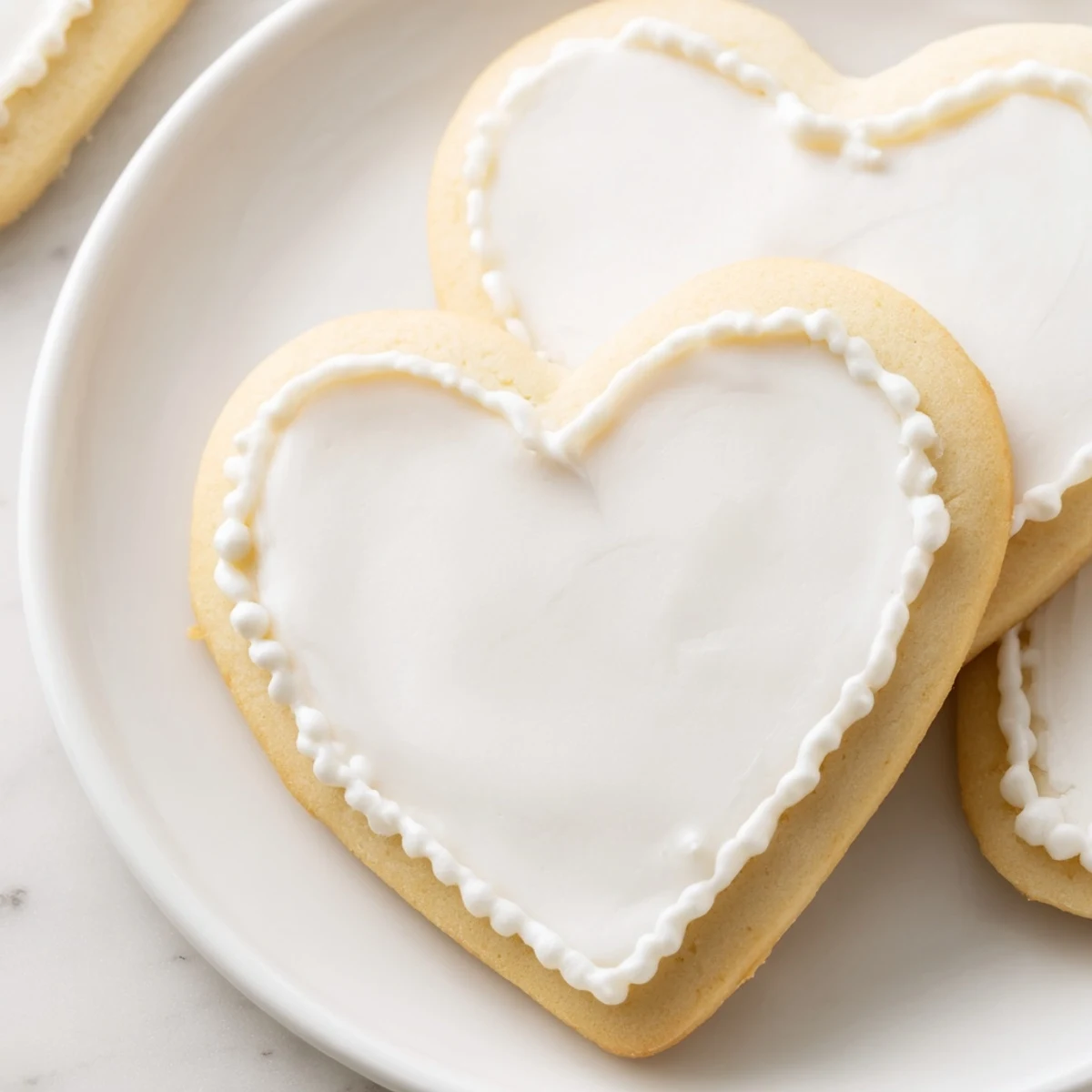 Freshly baked heart-shaped sugar cookies with smooth royal icing glaze, beautifully presented on a rustic wooden serving platter.