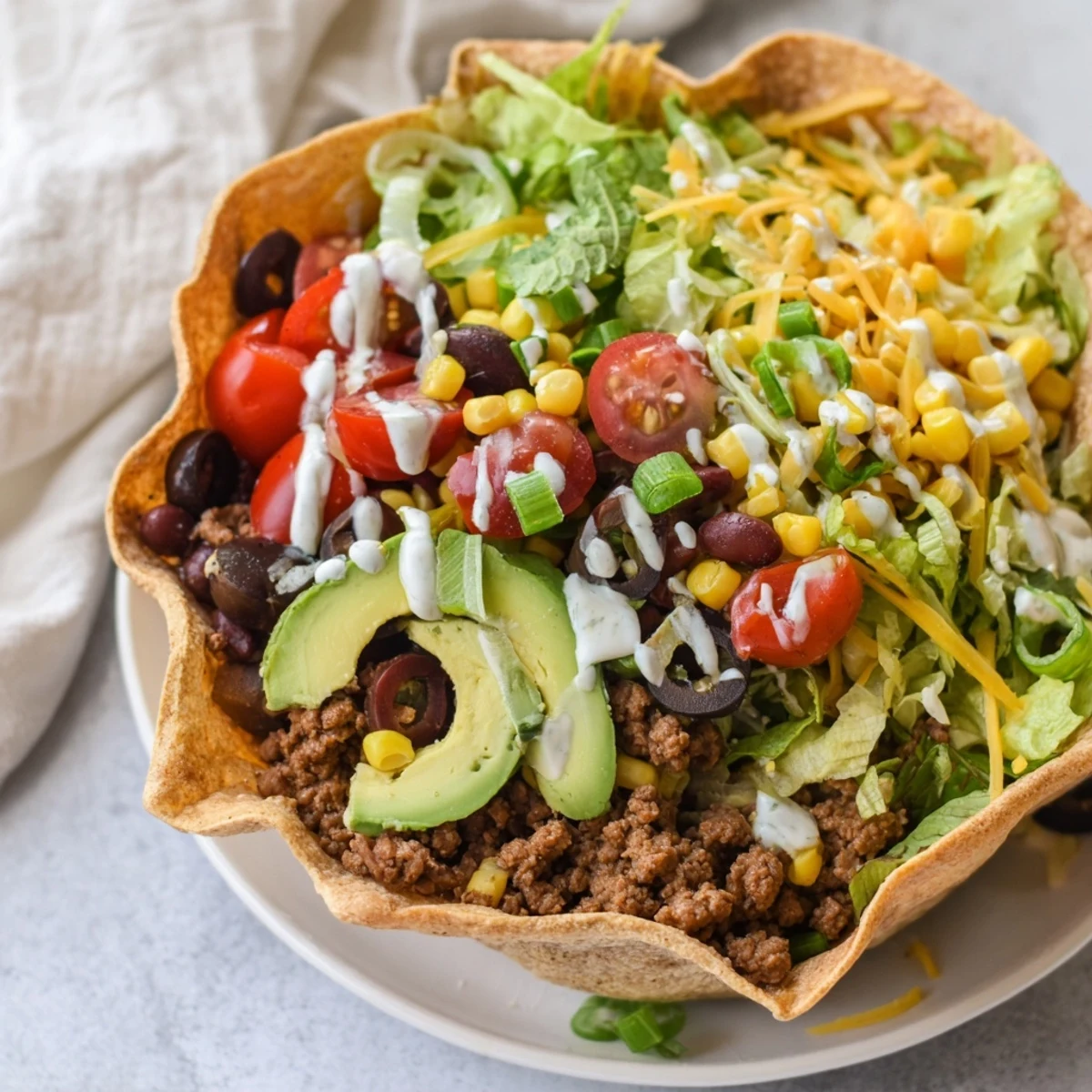 Freshly baked tortilla bowls serve a colorful Beef Taco Salad with seasoned beef, black beans, corn, and tangy dressing.