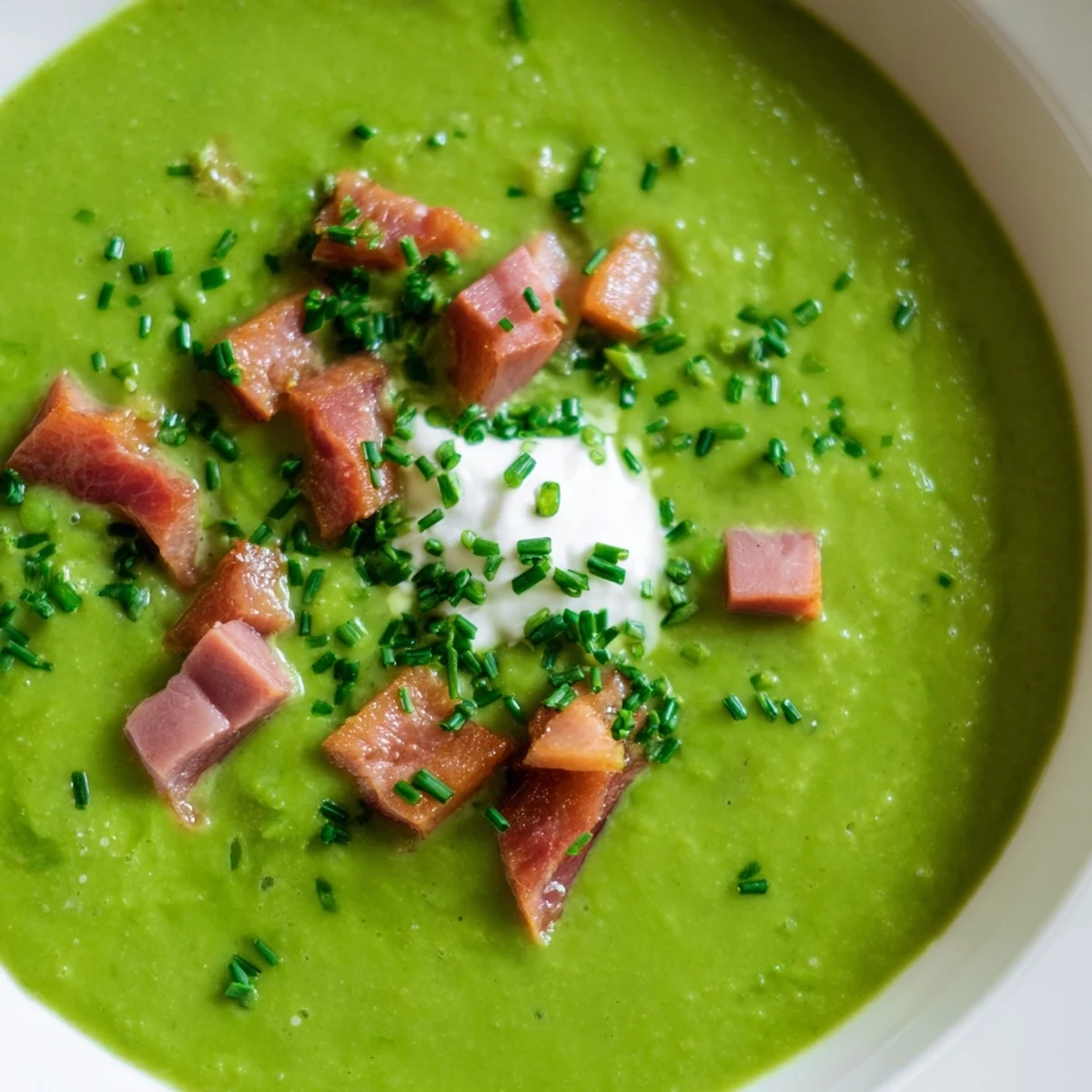 A bowl of Spring Pea Soup topped with crispy turkey bacon pieces and fresh chives garnish.