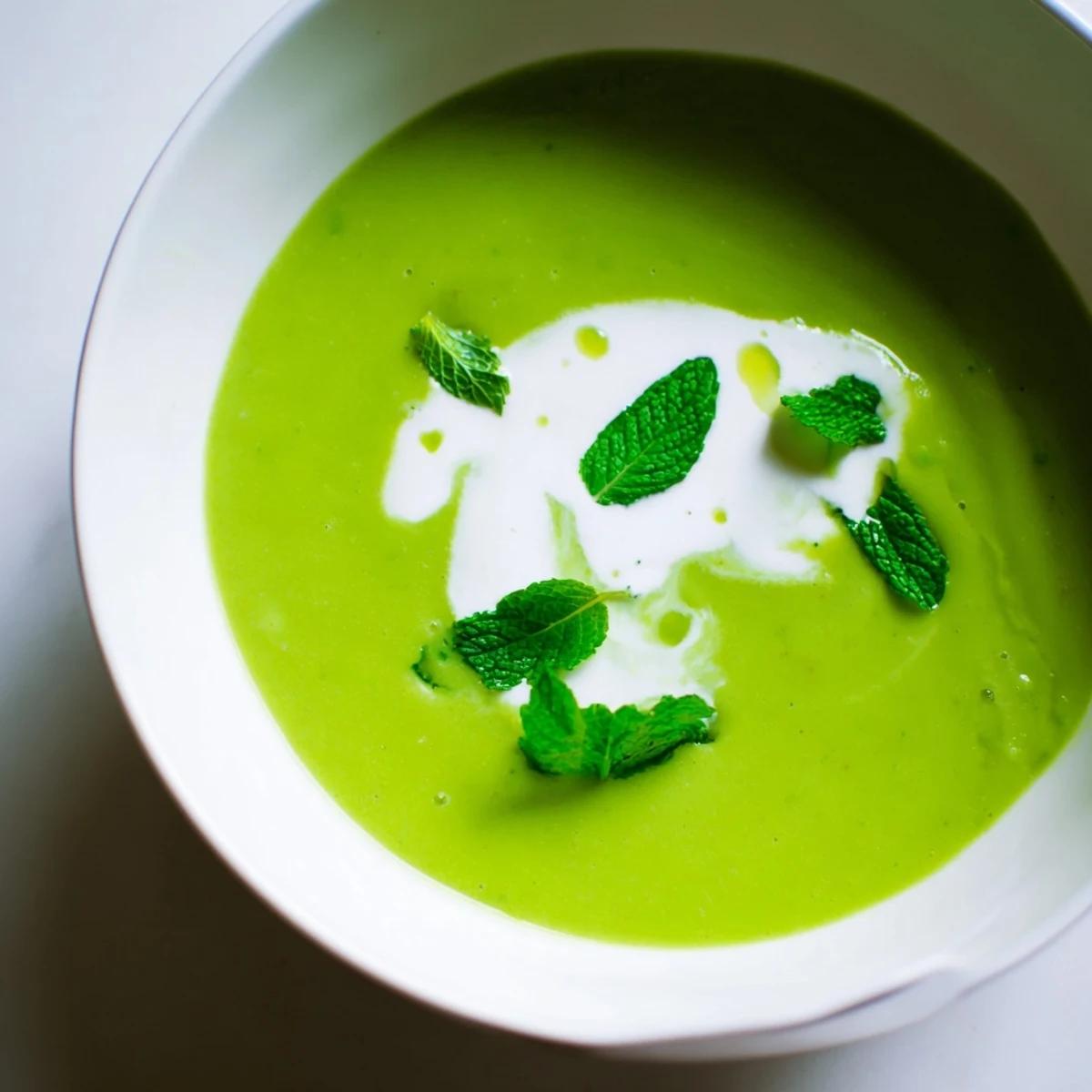 Spring Pea Soup with Mint and Crème Fraîche served warm in a rustic bowl, topped with a dollop of crème fraîche and lemon zest.