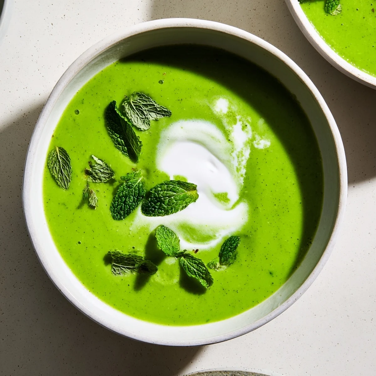 Overhead view of Spring Pea Soup with Mint and Crème Fraîche, showcasing the velvety texture and bright pea-green color.