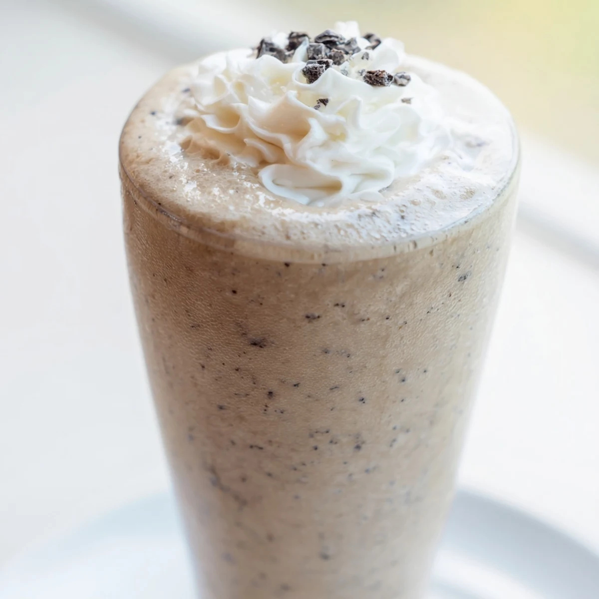 Creamy Vanilla Bean Frappuccino topped with whipped cream and white chocolate shavings in a tall glass.