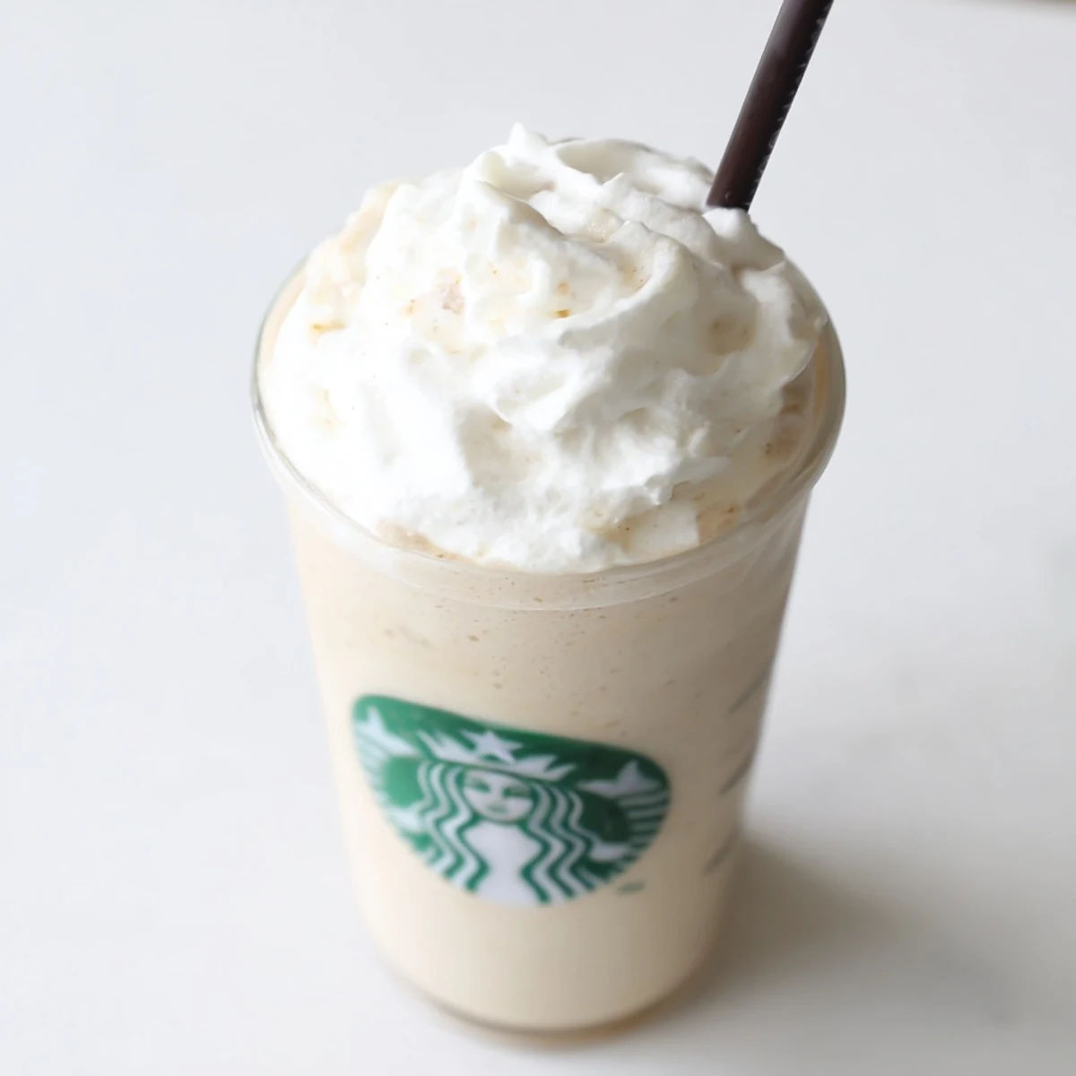 A photo of a creamy Starbucks Vanilla Bean Frappuccino topped with fluffy whipped cream in a tall glass, ready to sip with a straw.