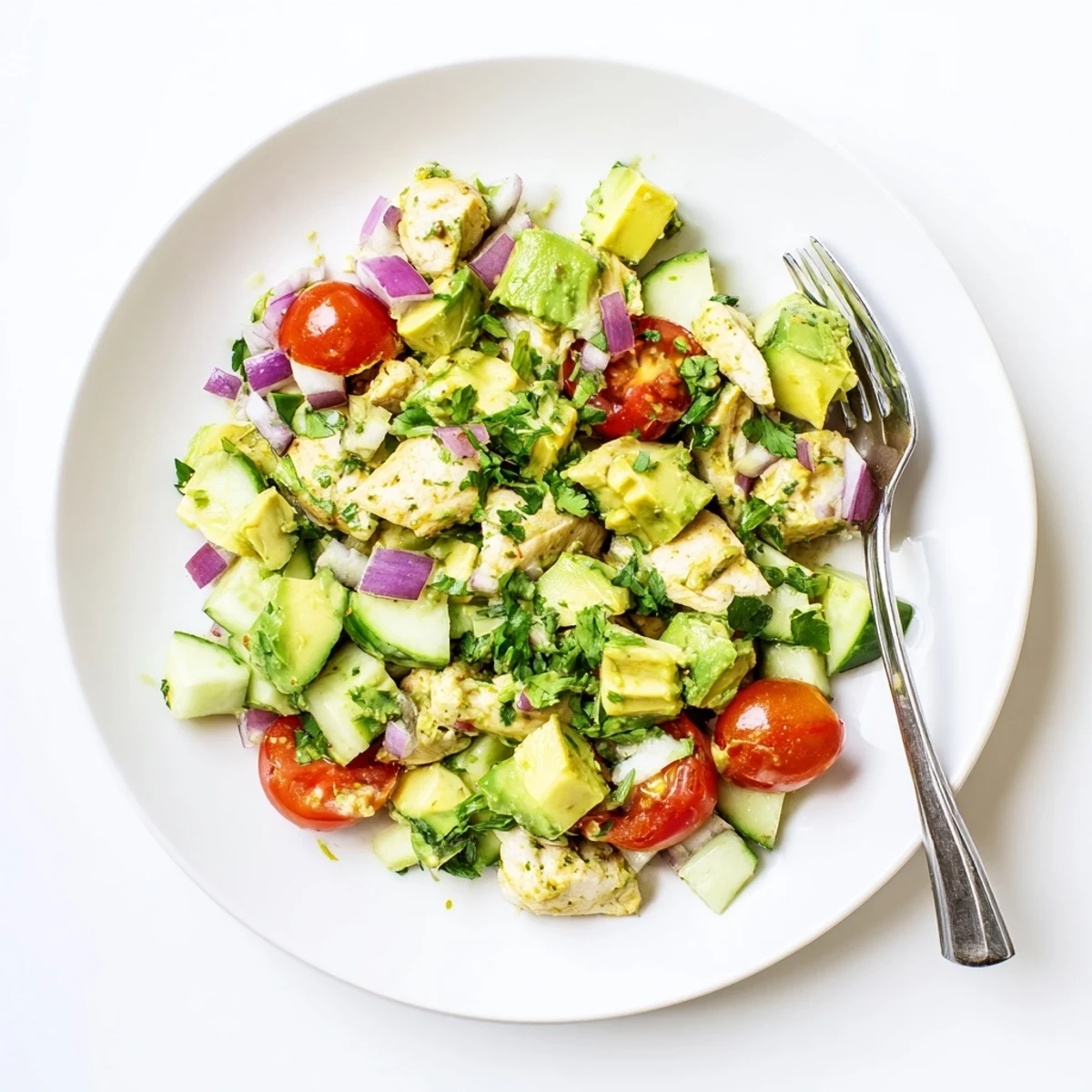 A hearty serving of Avocado Chicken Salad in a rustic bowl, garnished with parsley and ready for a light lunch or dinner, highlighted by a light dressing drizzle.