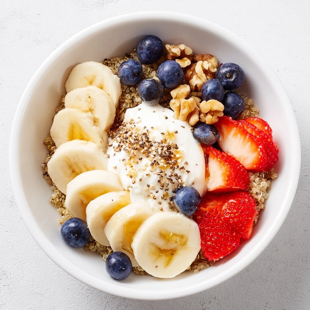 A vibrant Dietitians Balanced Breakfast Bowl with quinoa, Greek yogurt, berries, banana, and sliced eggs topped with nuts and chia seeds.