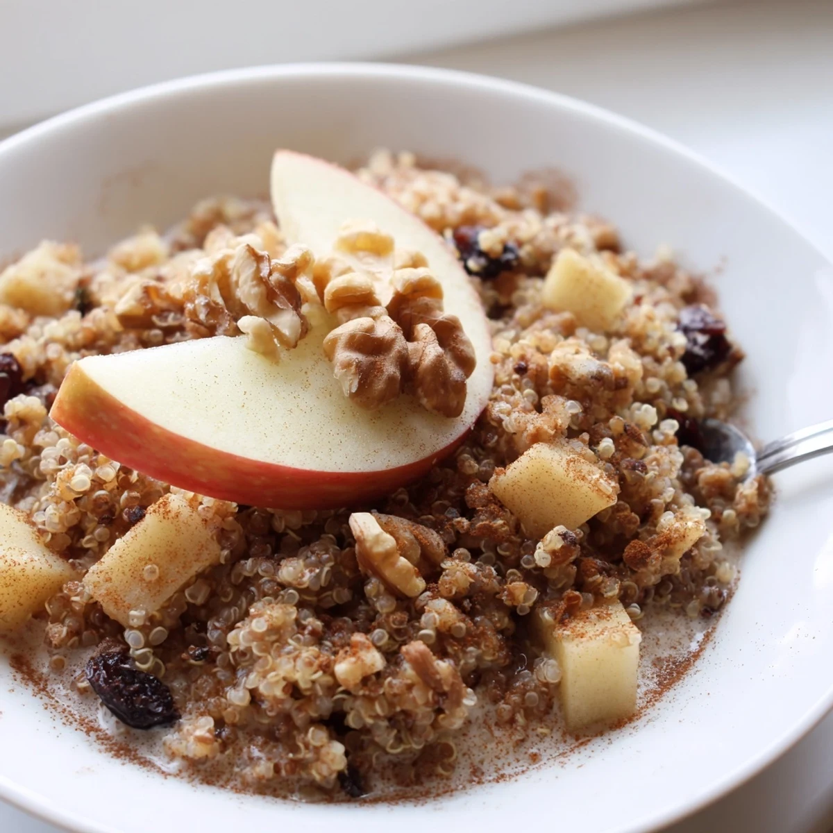 A warm bowl of Healthy Quinoa Apple Breakfast topped with crunchy walnuts and fresh apple slices.