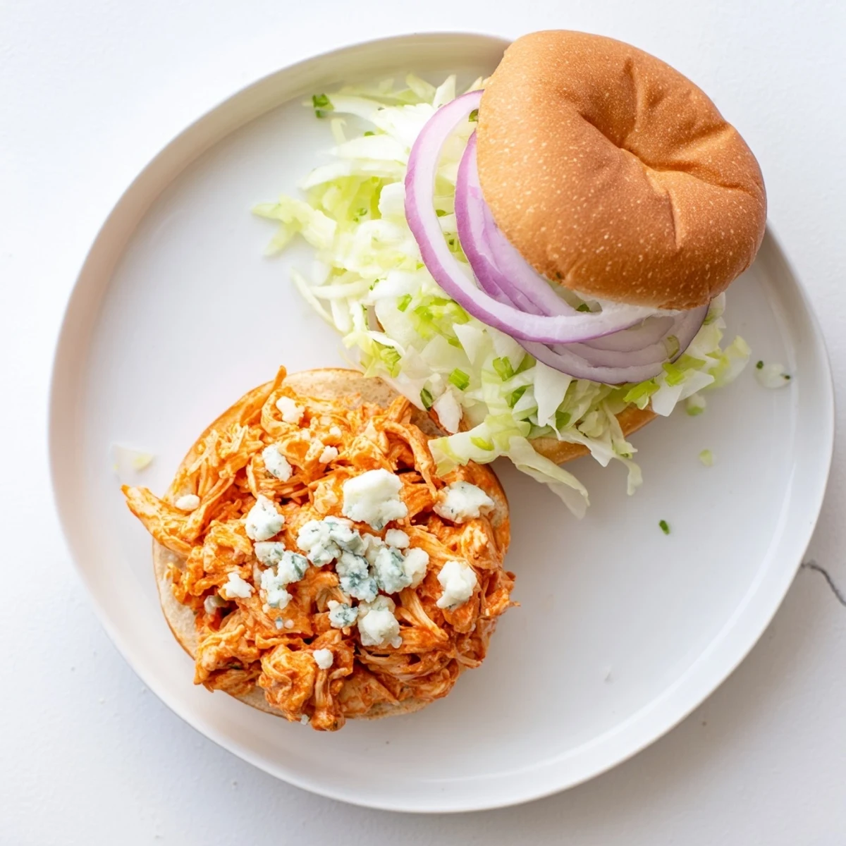 A close-up of Spicy Buffalo Chicken Sliders with shredded chicken, melted blue cheese, and crisp lettuce on toasted buns.
