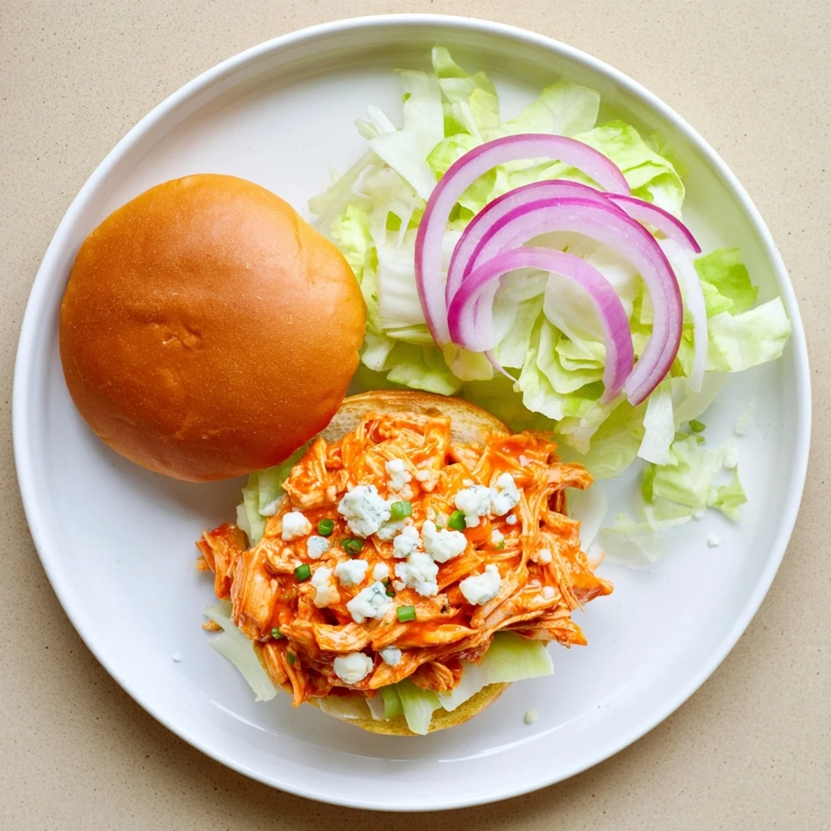 These golden-baked Spicy Buffalo Chicken Sliders feature spicy chicken, blue cheese crumbles, and crisp veggies on fluffy buns.
