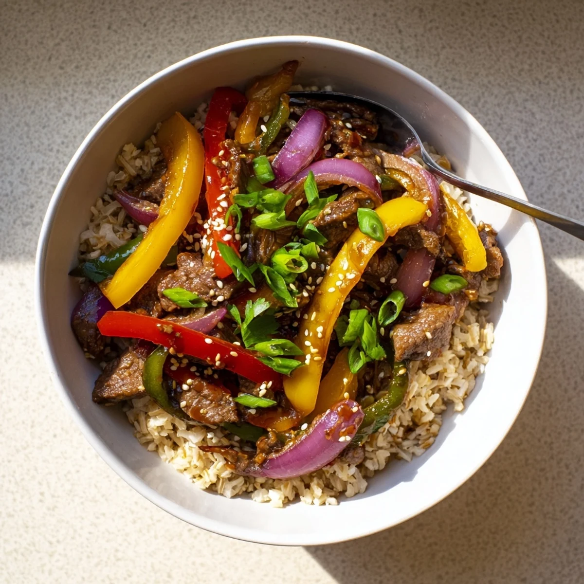 Close-up of Healthy Beef and Pepper Rice Bowl featuring glossy garlic-ginger sauce coating crisp peppers and savory beef strips.