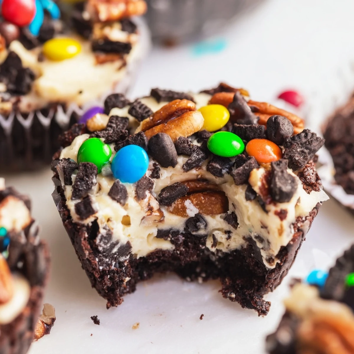 Rich fudgy loaded brownie cheesecake cups topped with colorful candy and chocolate chips