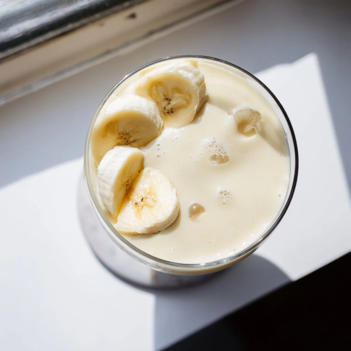 Thick protein-packed Greek yogurt banana smoothie blended with ice and vanilla in a clear cup