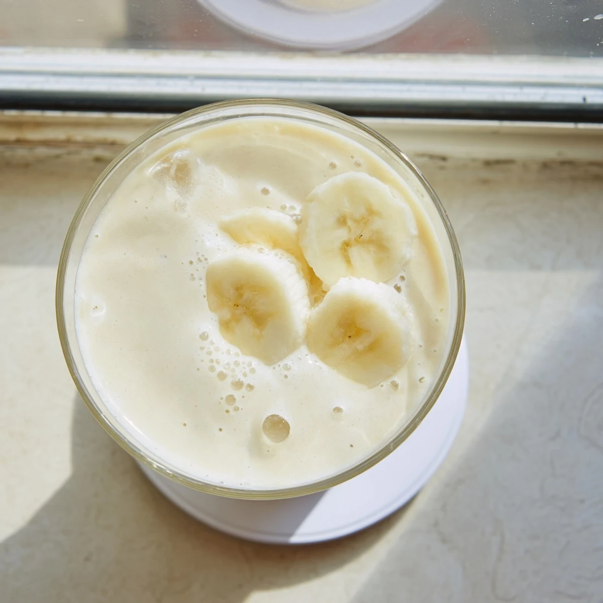 Golden Greek yogurt banana smoothie with cinnamon garnish resting on a wooden kitchen counter