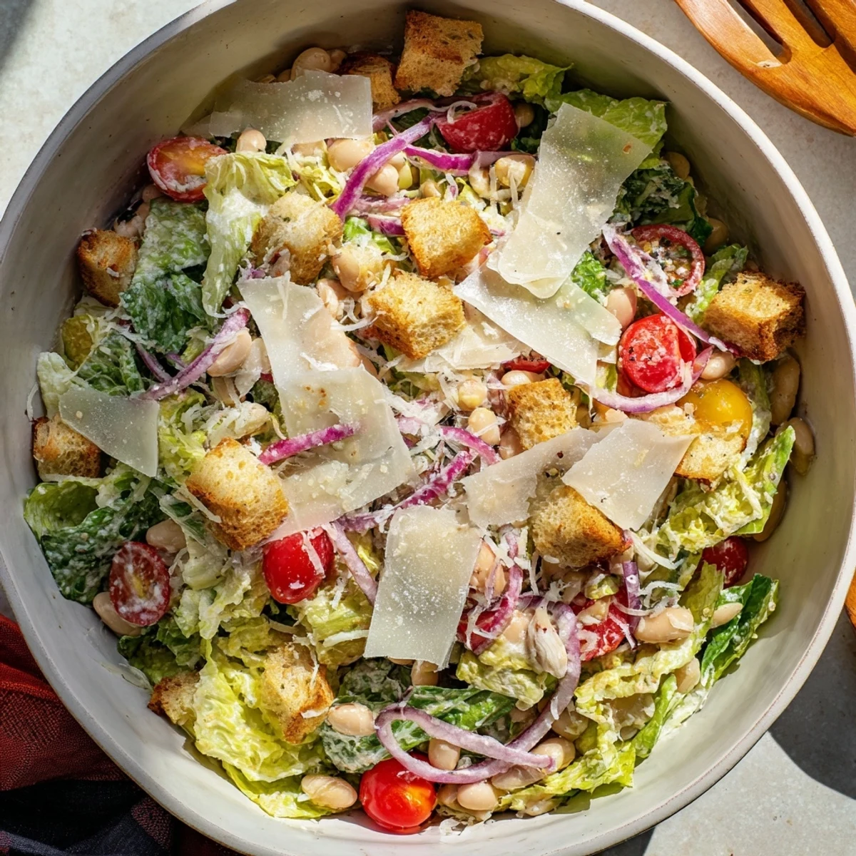 Protein-rich butter bean Caesar salad featuring cherry tomatoes and shaved Parmesan cheese