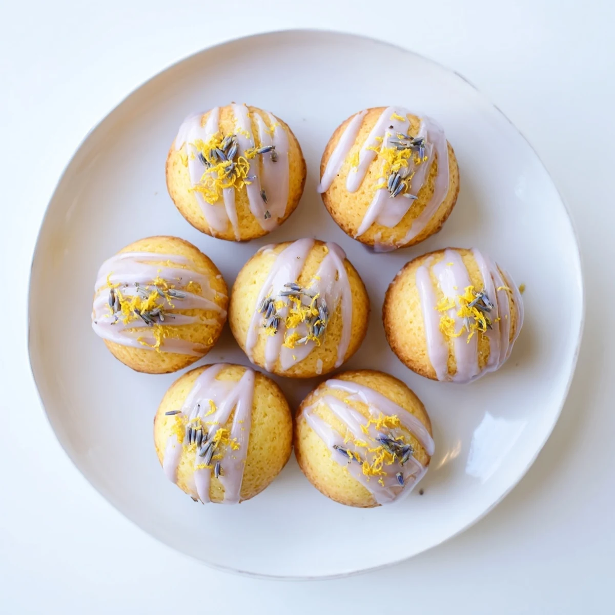 Freshly baked lemon mini cakes topped with purple-dotted white lavender glaze for spring desserts