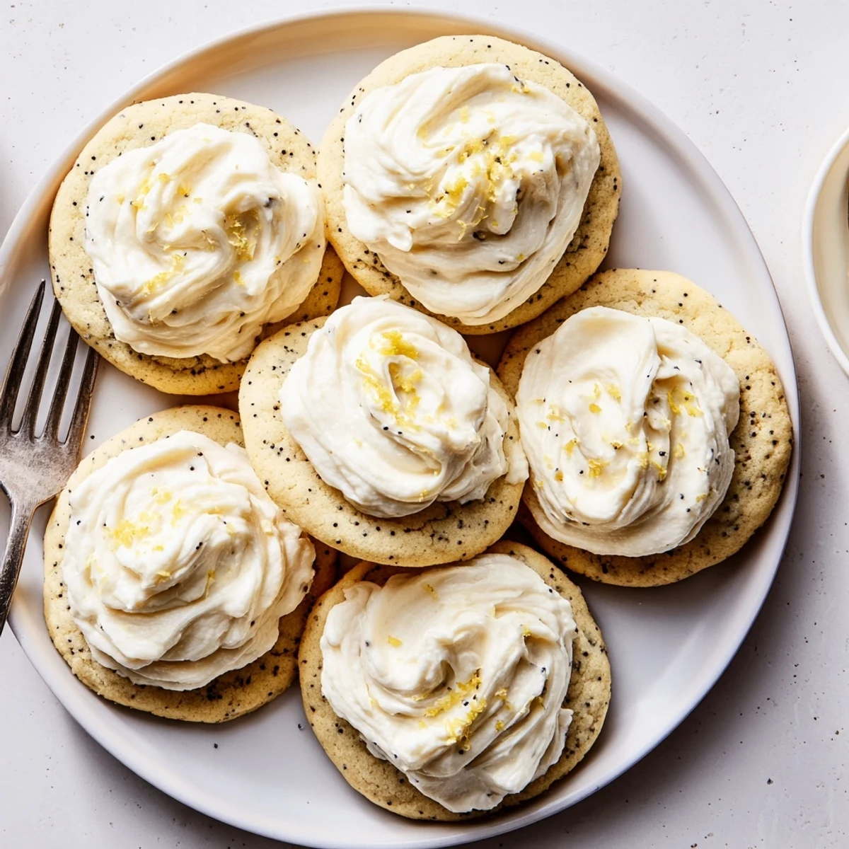 Plate of lemon poppy seed cookies with cheesecake frosting garnished with lemon zest sprinkles