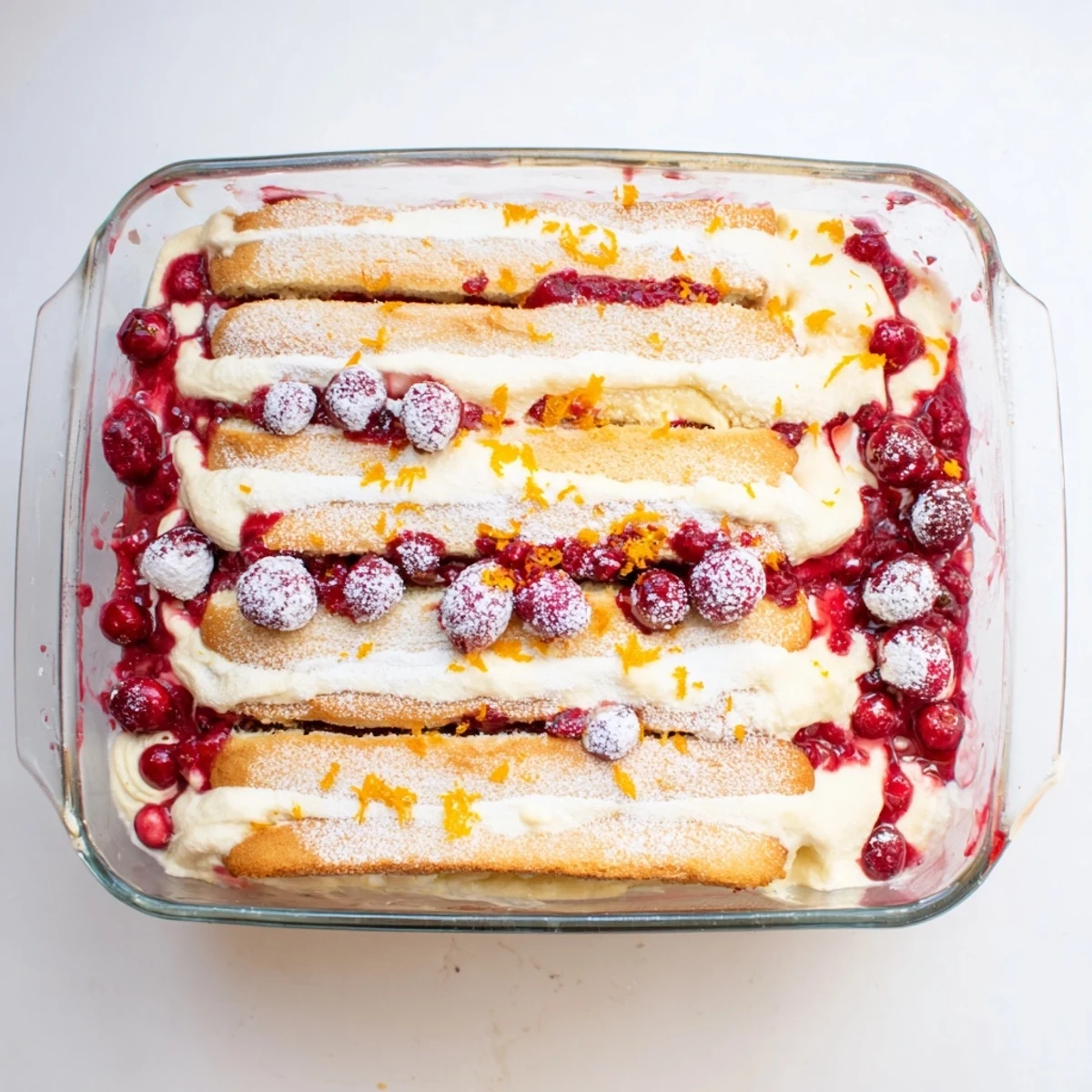 Festive Cranberry and Orange Tiramisu topped with fresh cranberries and orange zest on a white dessert plate.