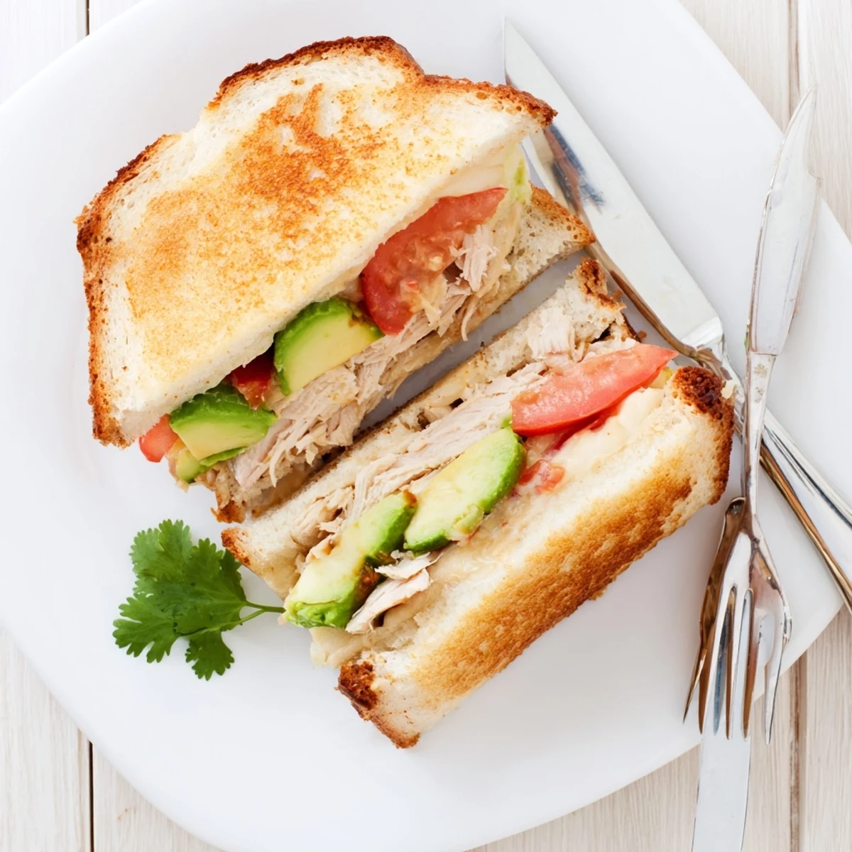 Half-cut chicken avocado melt sandwich revealing juicy chicken, melted cheese, and ripe avocado filling
