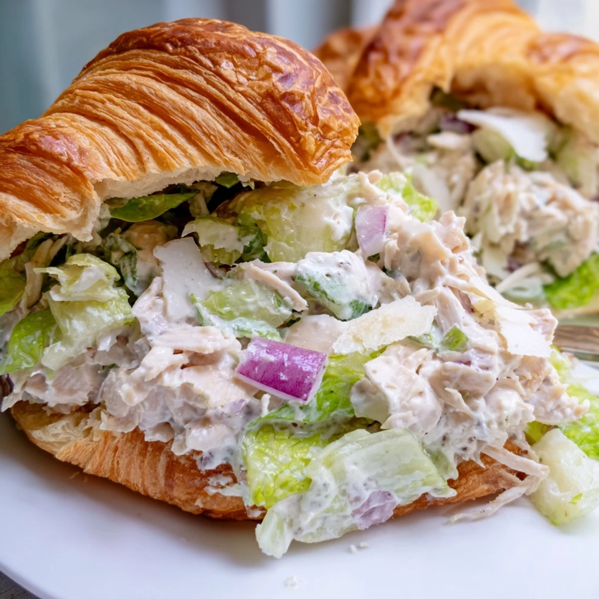 Golden croissant brimming with creamy Caesar chicken salad and crisp romaine lettuce