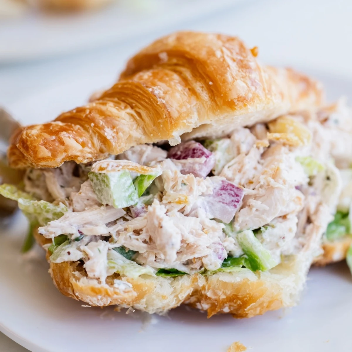 Buttery croissant sandwich overflowing with Parmesan chicken salad and fresh crunchy vegetables