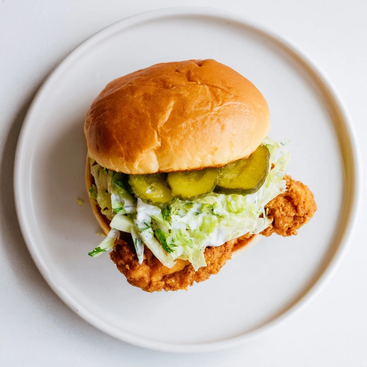 Handheld crispy dill chicken sandwich showcasing golden fried fillet with shredded lettuce