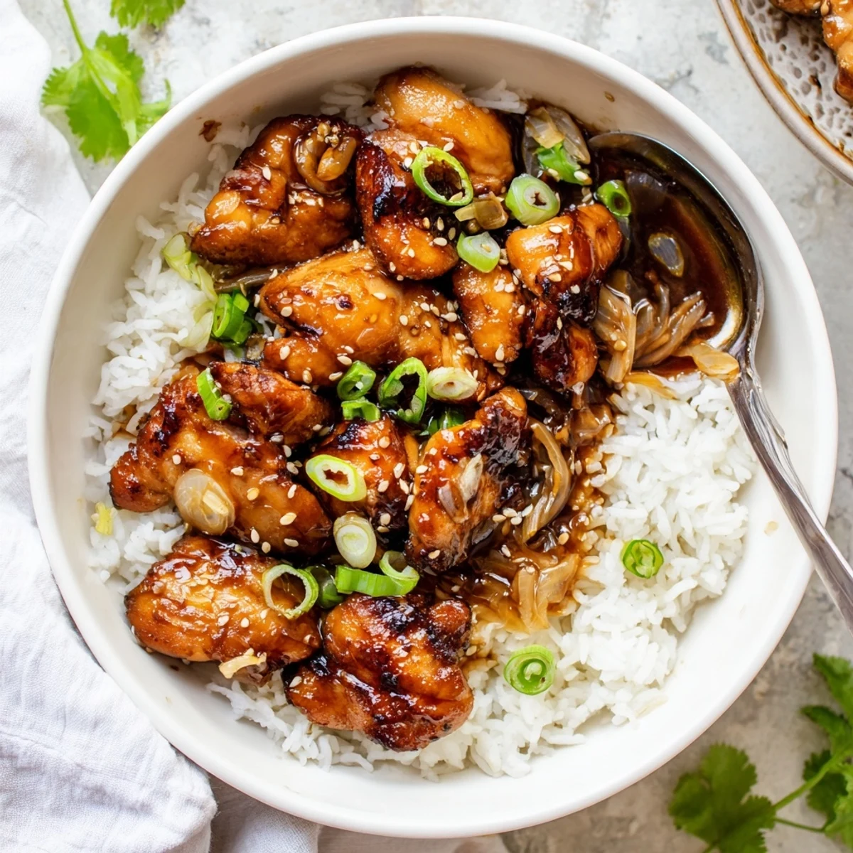 Bowl of caramelized soy chicken in aromatic broth garnished with fresh spring onions and sesame seeds