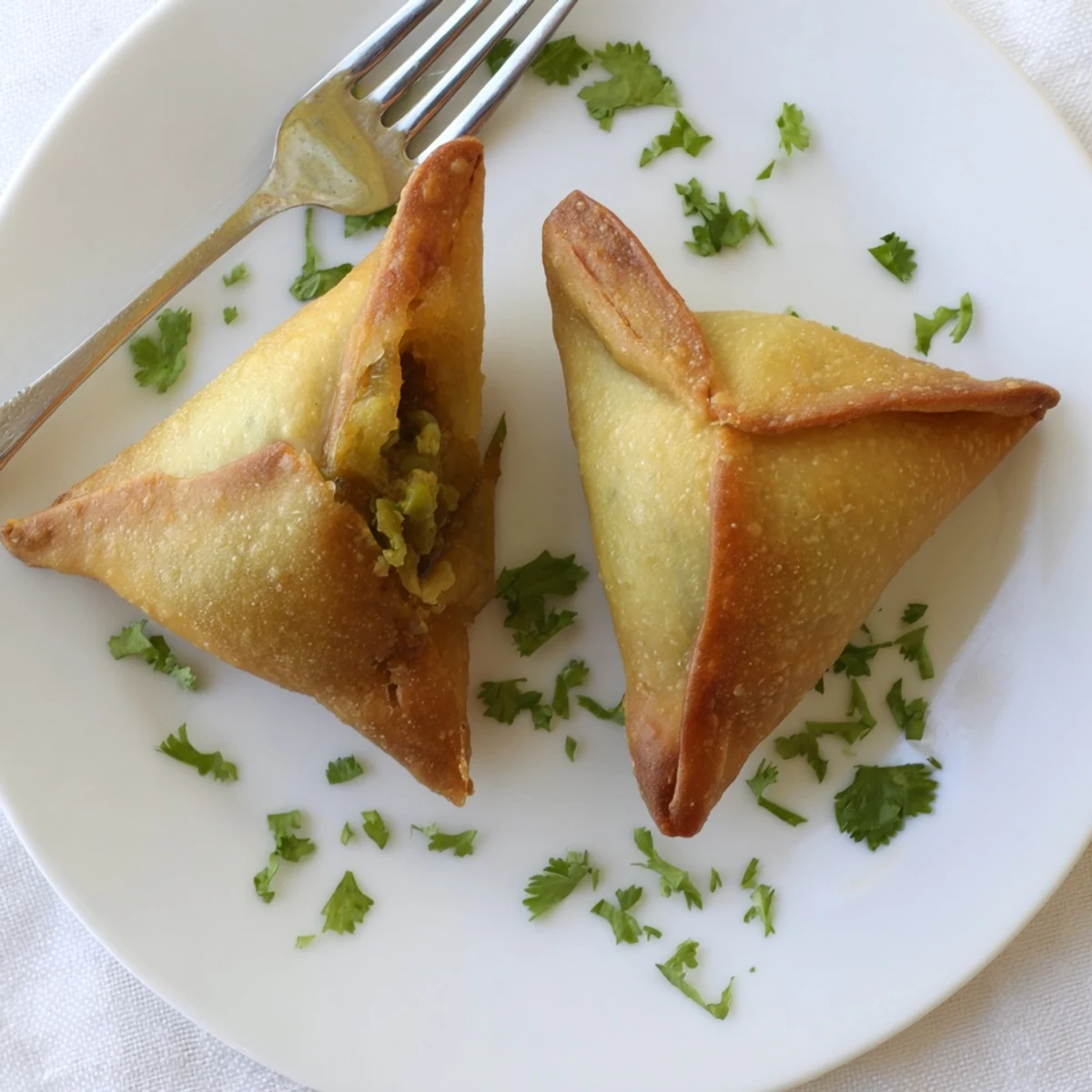 Triangle shaped vegetable samosas fried to golden perfection with aromatic herb and potato stuffing