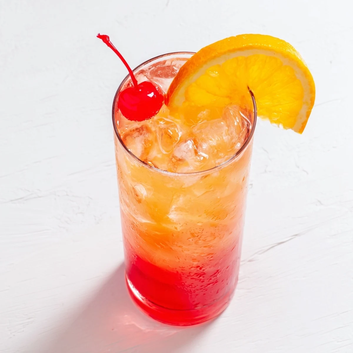 Tall glass filled with rosy Easy Shirley Temple Drink topped with bright red cherry