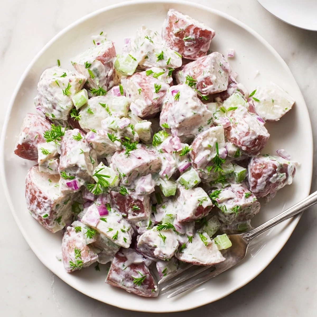 Hearty red potato salad dressed in creamy mustard sauce, garnished with chives for summer picnics