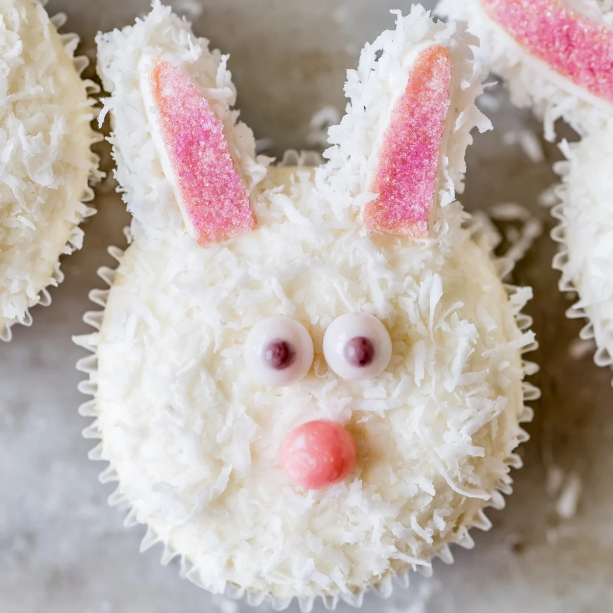Frosted bunny cupcakes decorated with marshmallow ears, jelly bean noses, and fluffy coconut coating for Easter desserts