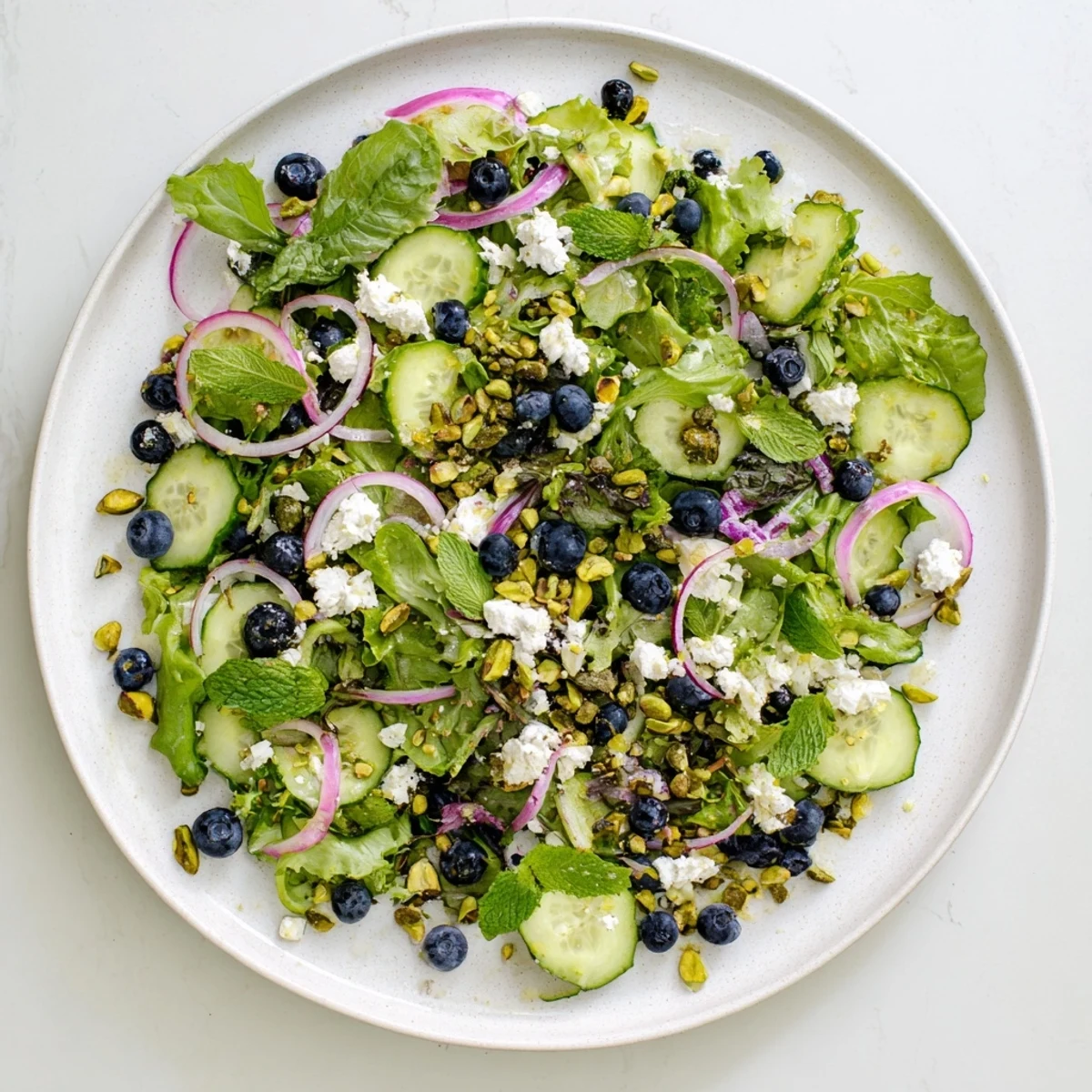 Fresh blueberry pistachio spring salad with juicy berries, crunchy nuts, and crisp greens in a bowl