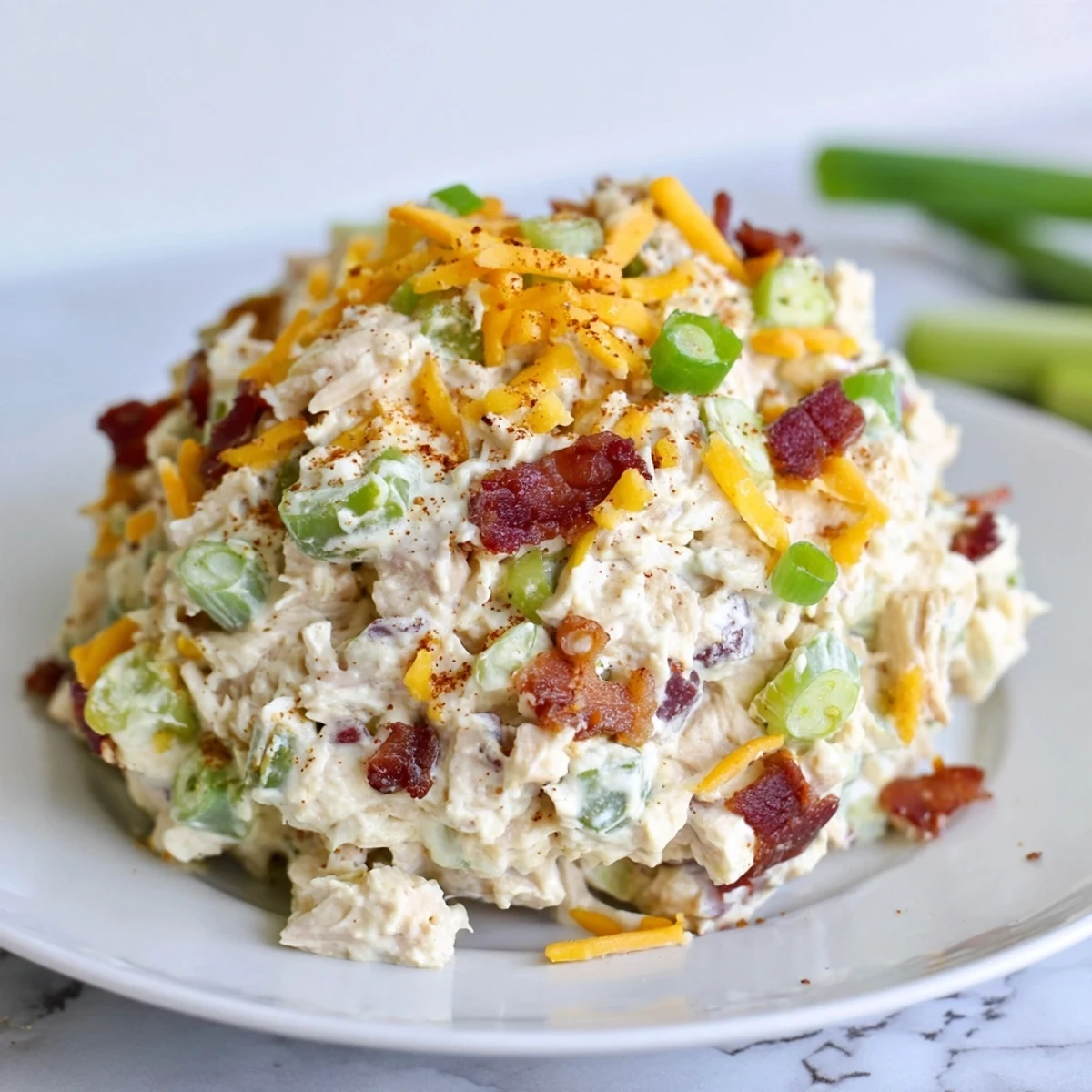 Spicy jalapeno popper chicken salad featuring crisp bacon bits, diced celery, and shredded cheese topping