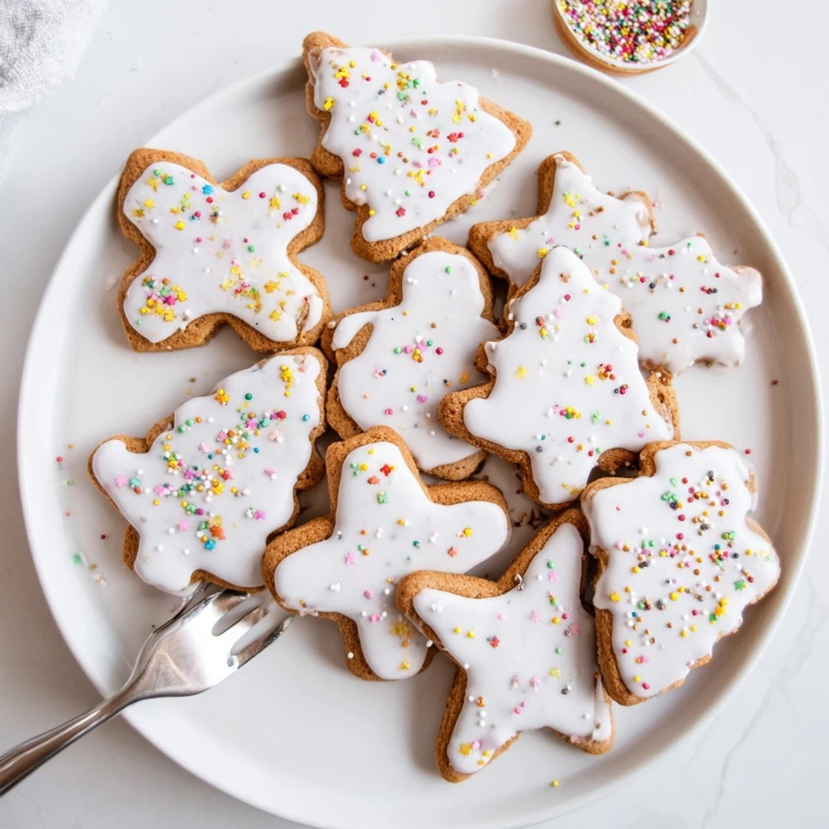 Soft golden gingerbread cookies decorated with white icing and colorful sprinkles on a wooden cutting board