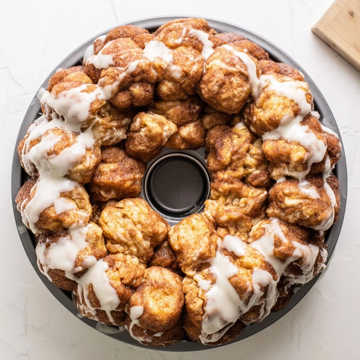 Pull-apart high protein no sugar monkey bread drizzled with creamy vanilla glaze on serving plate