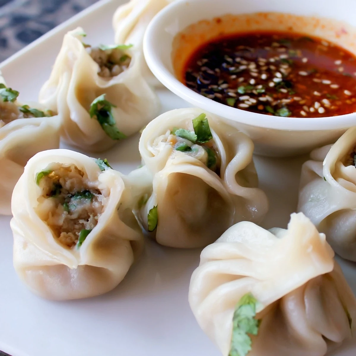 Steaming hot Nepali momo dumplings arranged on a bamboo steamer with pleated edges