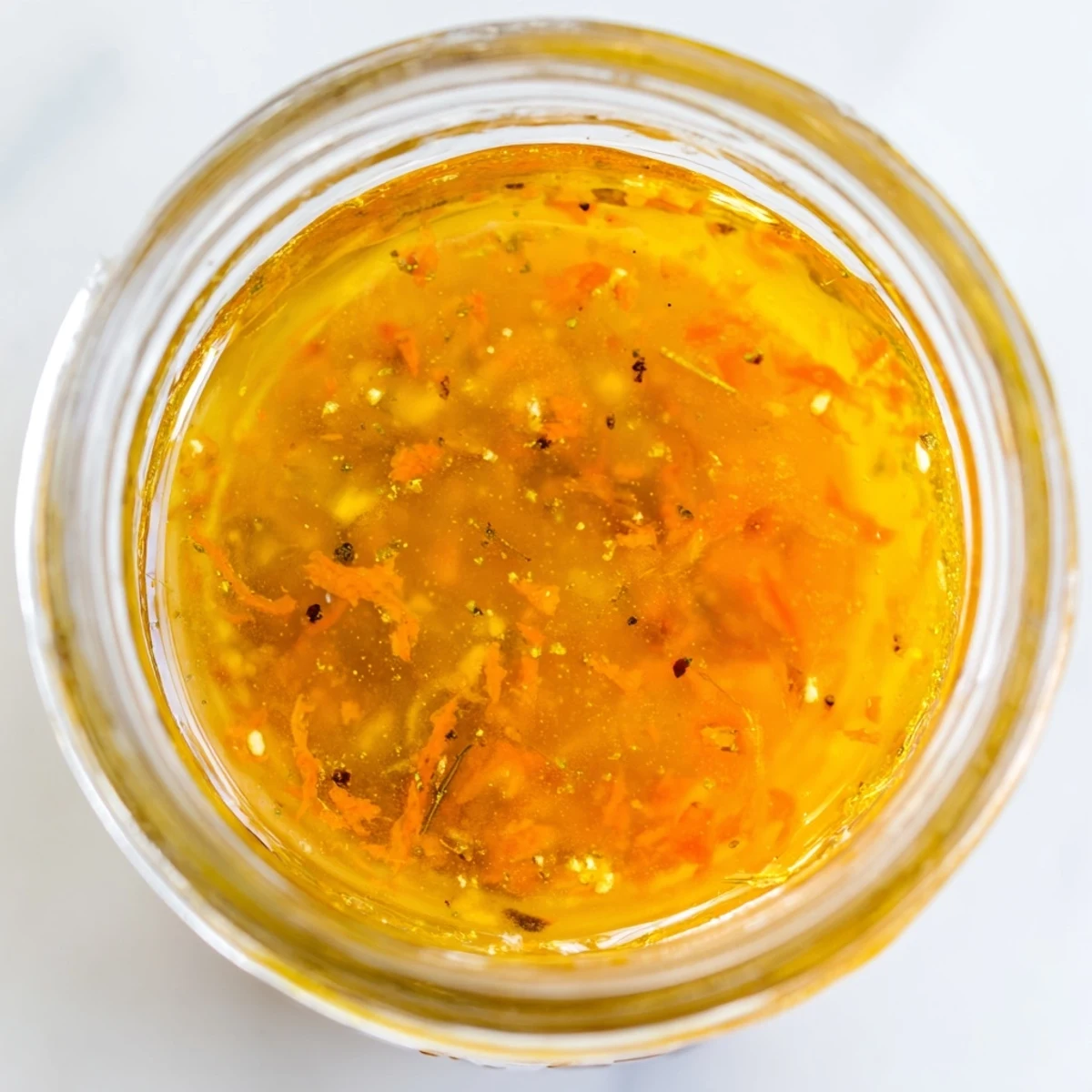 Golden citrus vinaigrette drizzling from a spoon over crisp mixed greens