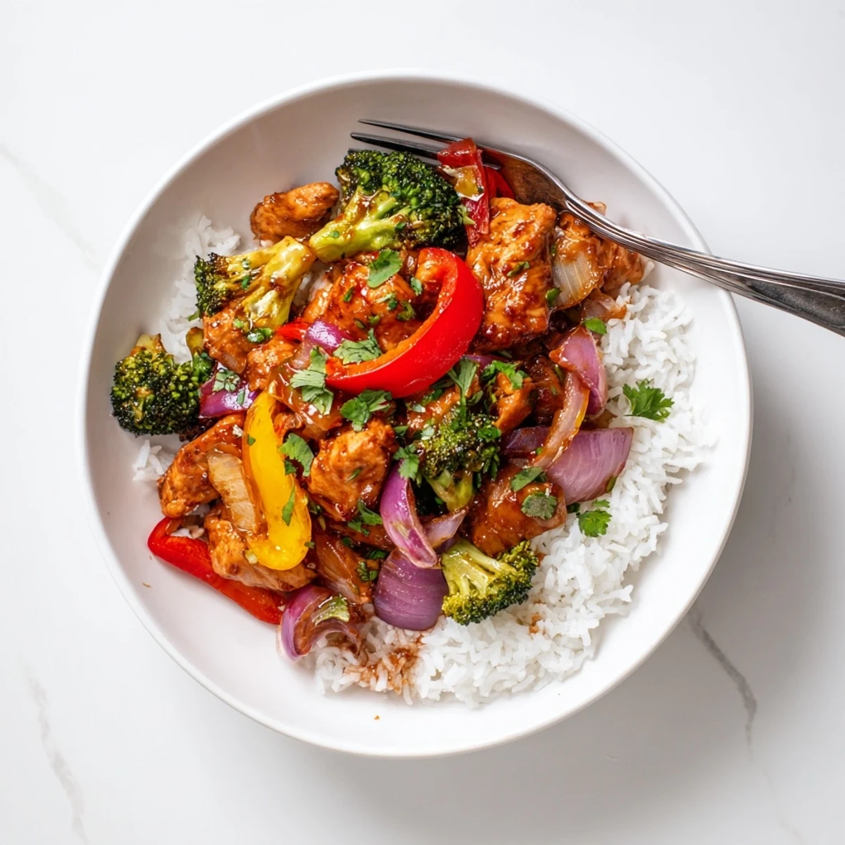 Colorful chicken and vegetable stir fry sizzling in a glossy sauce on white rice