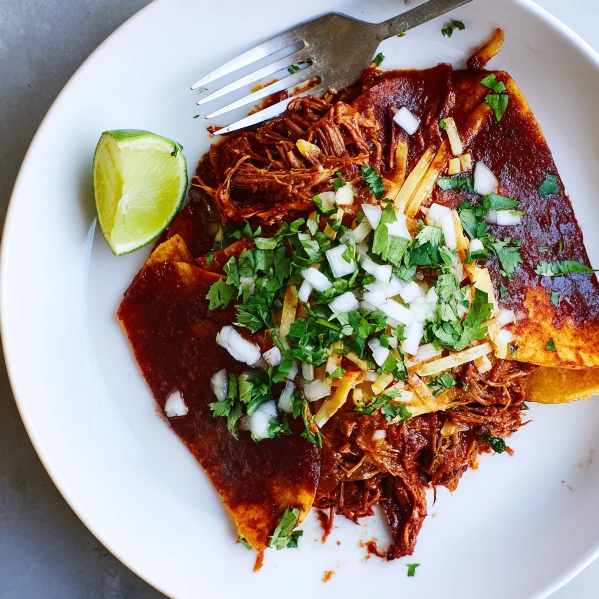 Slow cooker birria tacos with shredded beef in a rich red consommé
