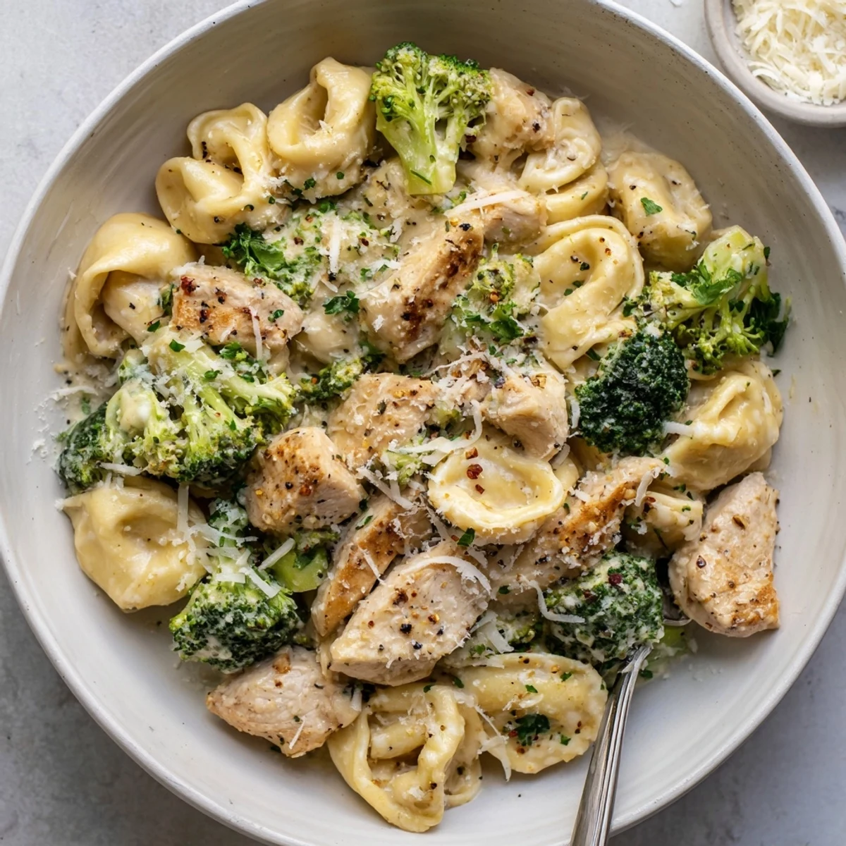 A weeknight bowl of Creamy Garlic Parmesan Tortellini Chicken Broccoli Recipe with crusty bread