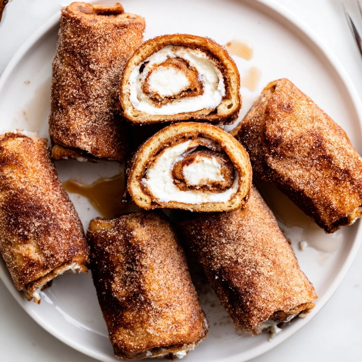 Cinnamon Roll French Toast Roll Ups frying golden in butter, ready for maple