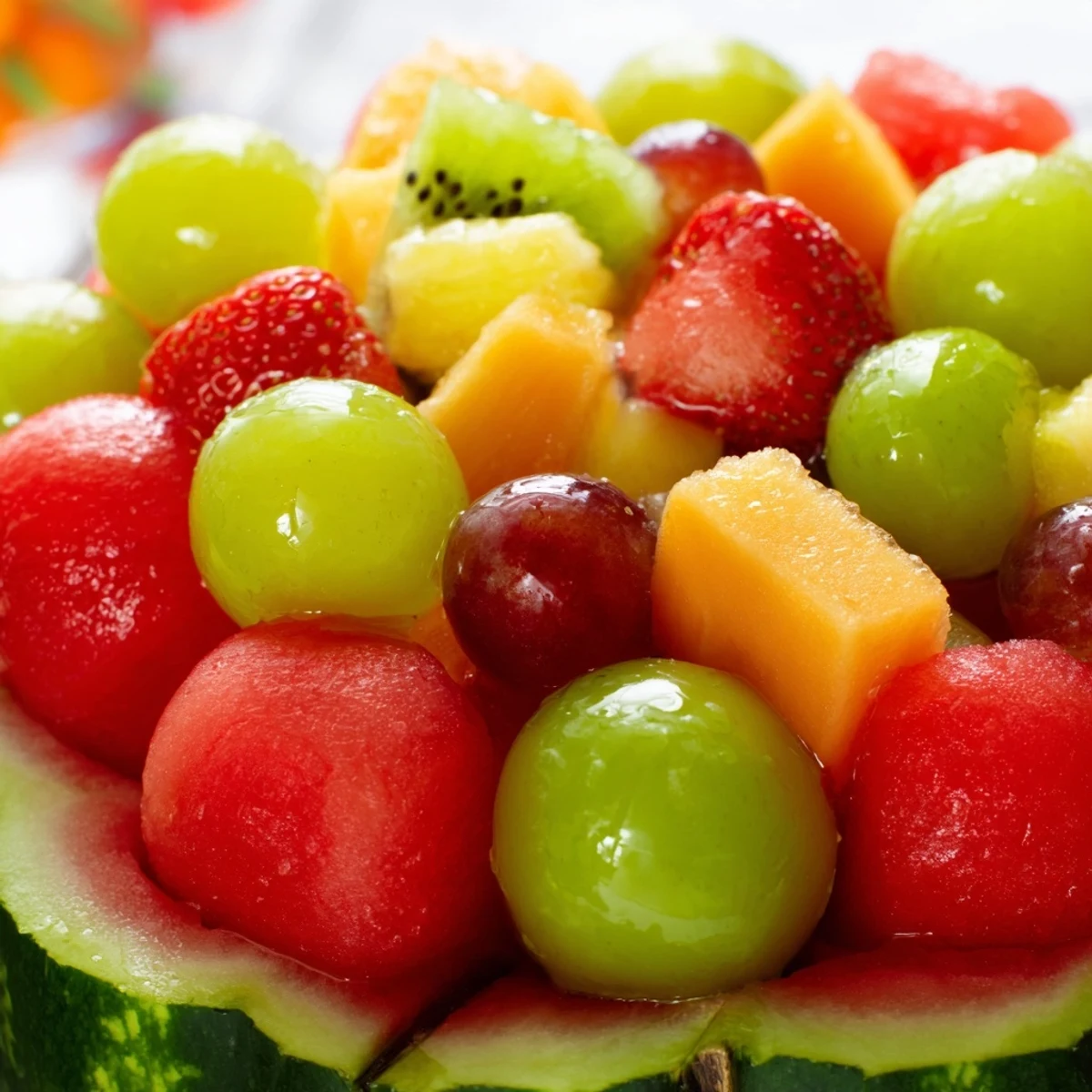 Carved watermelon basket overflowing with colorful fresh fruit salad for summer parties