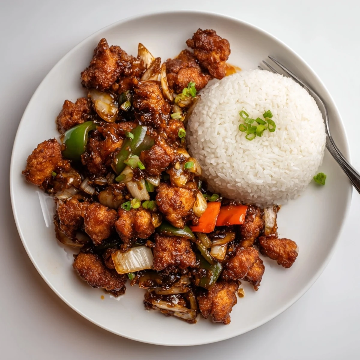 Steaming Flavorful Chilli Chicken Indo Chinese served over jasmine rice, scallion garnish.