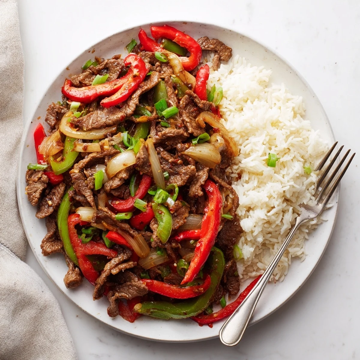 Sizzling spicy beef stir fry with chili garlic sauce served over fluffy white jasmine rice