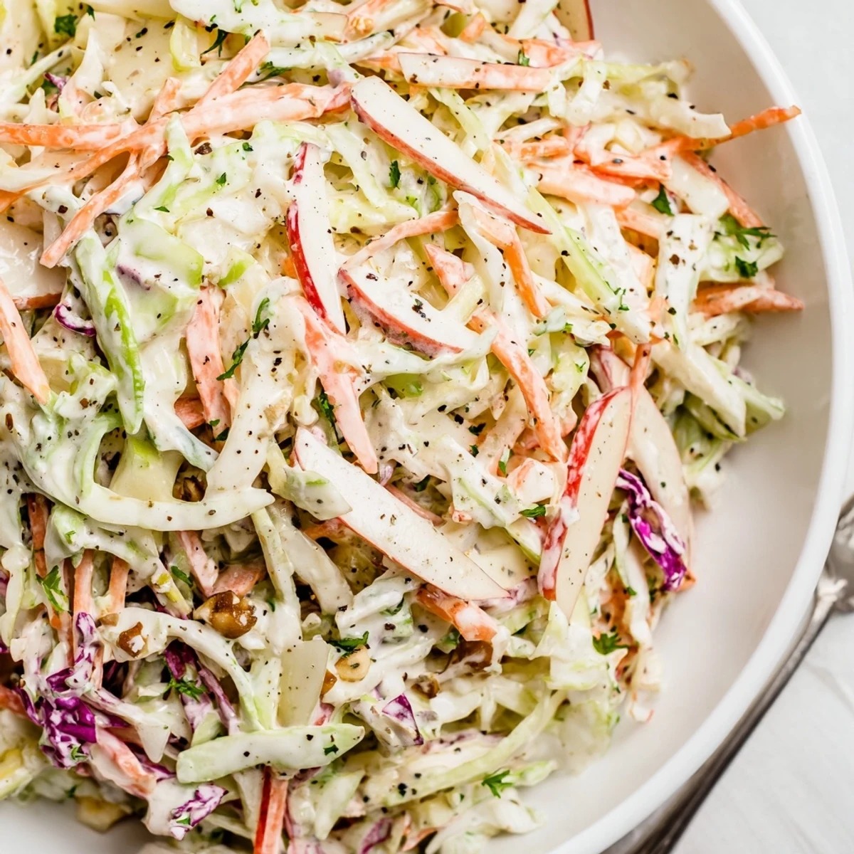 Creamy Apple Coleslaw topped with toasted pecans, crisp slaw for BBQ.